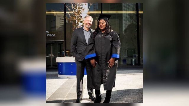 Female college graduate in a cap and gown standing next to the man who helped her out financially